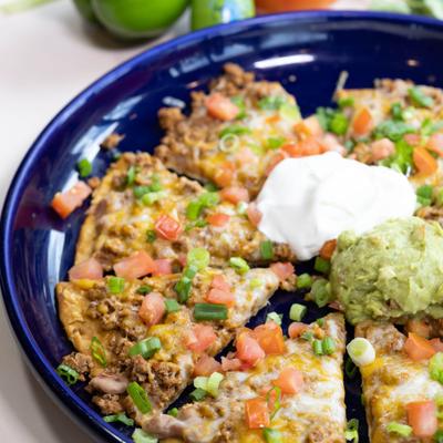 Mexican pizza topped with chopped scallions, sour cream, and guacamole.