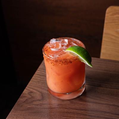 A refreshing red cocktail, rimmed with spice, and garnished with lime.