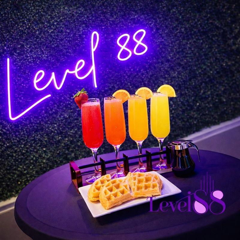 Mimosa flight served on the table with waffles and a neon sign in the background.
