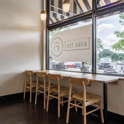 Interior with a wooden counter and six chairs by a large window.