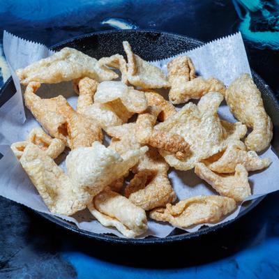 Fried pork rinds served on a plate lined with paper.