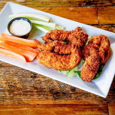 Chicken tenders served with a dipping sauce, carrot and celery sticks.