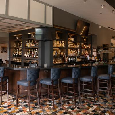 Bar area featuring dark wood shelving, a counter and blue-gray bar stools.