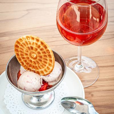 Ice cream served with an Italian waffle cookie, and a glass of rosé