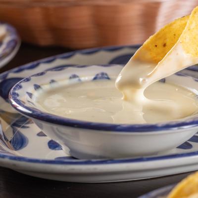 Tortilla chips being dipped in Cheese dip.
