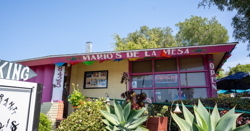Exterior, front view, entrance to restaurant, plants in front, name sign on a top of a porch
