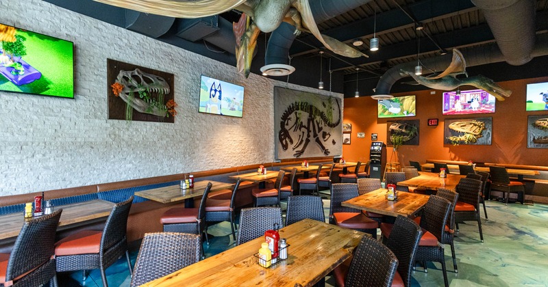 A restaurant interior with wooden tables, woven chairs, and dinosaur-themed decor