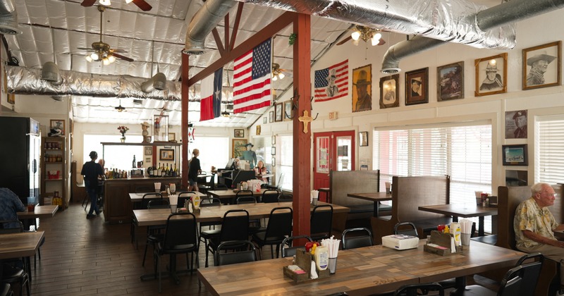 Interior, rustic-style restaurant with wooden tables and booth seating with simple black chairs