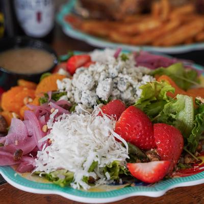 A salad with lettuce, strawberries, coconut, gorgonzola, and pickled onions.