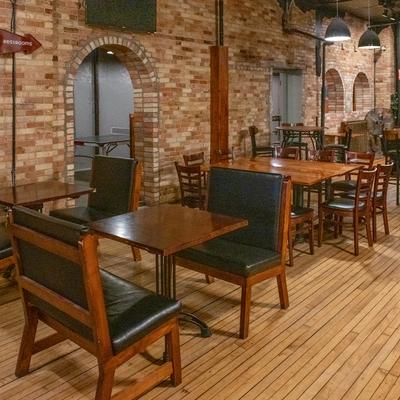 Interior, room featuring tables and chairs arranged in front of a rustic brick wall.