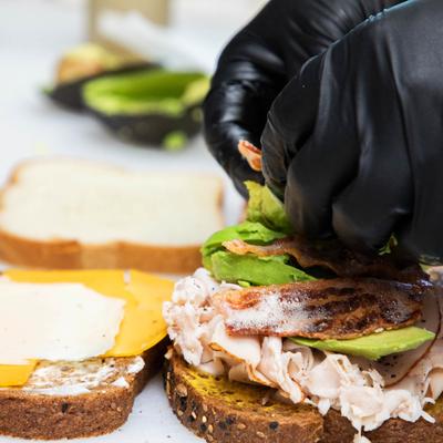 Hands with gloves fixing up a sandwich