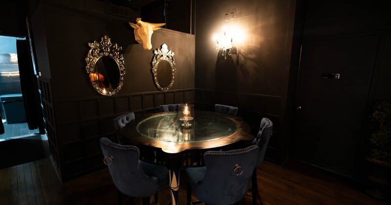 Interior, ornate dining room with a round glass-topped table, upholstered chairs, decorative mirrors
