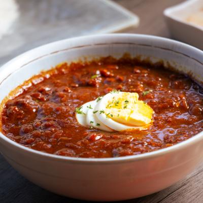 A bowl of beef and vegetable curry garnished with a hard boiled egg.