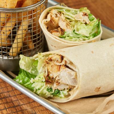 Crispy French fries in a metal basket and a grilled chicken and lettuce wrap