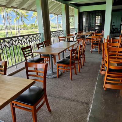Restaurant patio featuring wooden furniture and green landscape view.