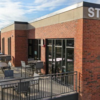 Outdoor rooftop terrace with a red brick wall and seating area.