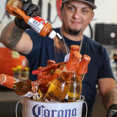 A bartender seasoning a bucket of Mexican beer with tajin.