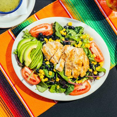 Santa Fe Salad topped with grilled chicken, avocado, black beans, and corn.