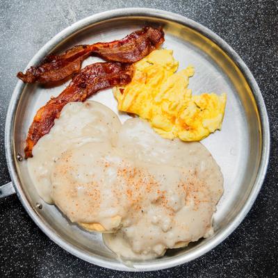 Biscuits with gravy served with crispy bacon and scrambled 'eggs.