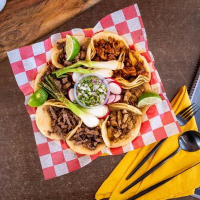Assorted street tacos platter with beef, chicken, and pork, served with lime and onions.