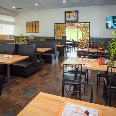 Restaurant interior with wooden tables, black booths, and decorative bamboo plants.