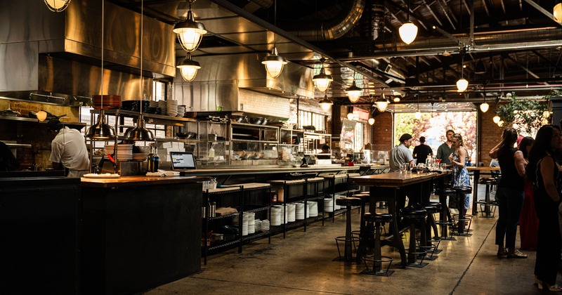 A modern, stylish, and cozy restaurant interior with an open kitchen concept