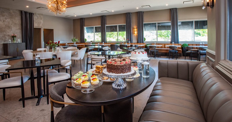 A modern dining area with tables, chairs, and a display of assorted desserts