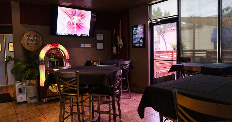 High tables with a black tablecloth and upholstered stools near the jukebox machine