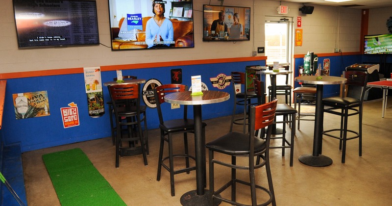Interior, tall tables and bar chairs, bar sticker decorations and TVs on the wall