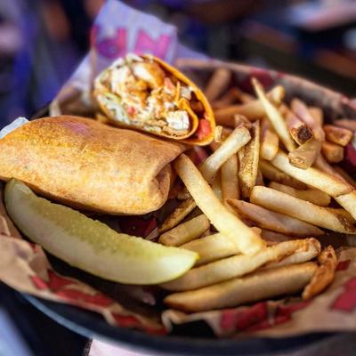 Chicken wrap with fries and a pickle spear.