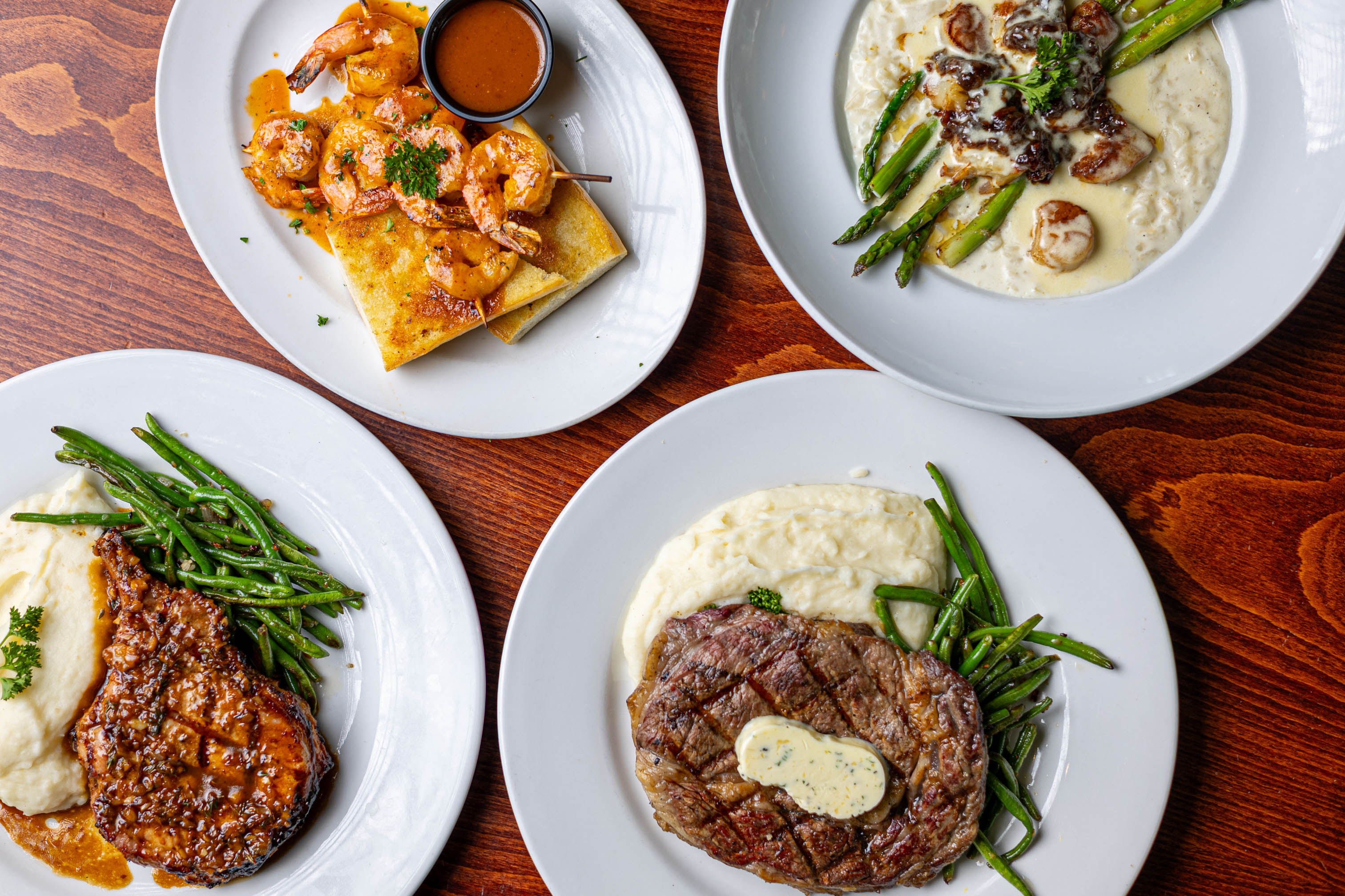 Four plated entrees including steak, shrimp, and vegetables