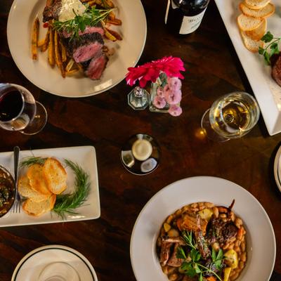 A table spread with assorted food plates and glasses of wine, overhead view.