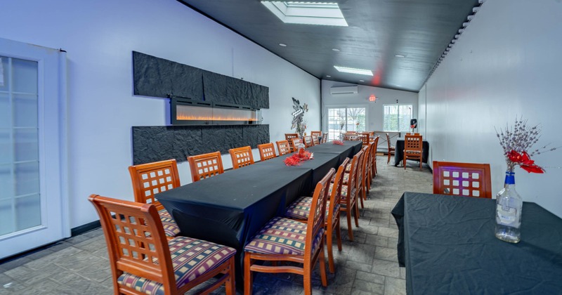 Long dining room with a black-clothed table, wooden chairs, an electric fireplace, and skylights