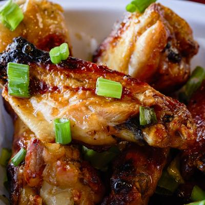 Glazed chicken wings with scallion garnish.