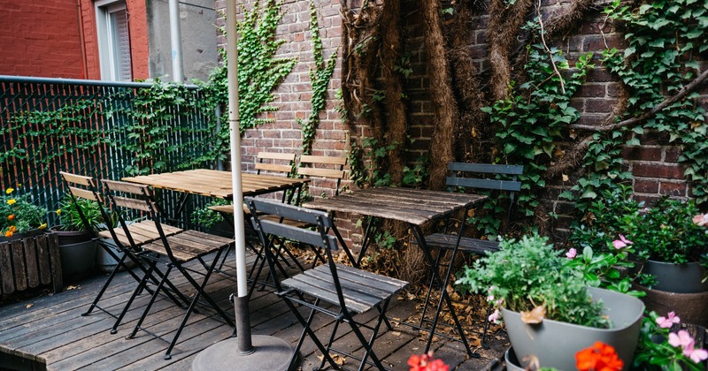 Exterior, wooden tables and chairs by the wall