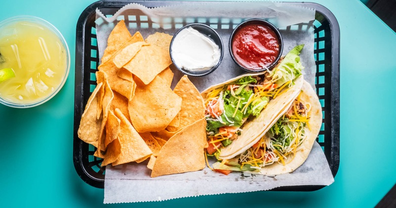 Tacos, nacho chips, sour cream, and salsa