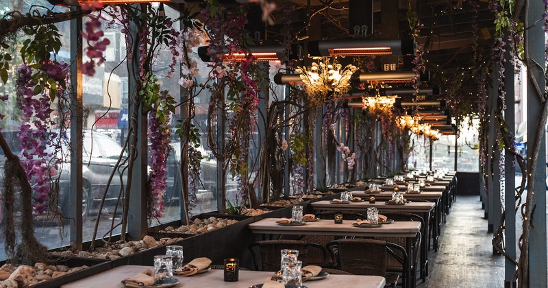 Covered patio with dining set tables, flower decoration and heaters on the celaing