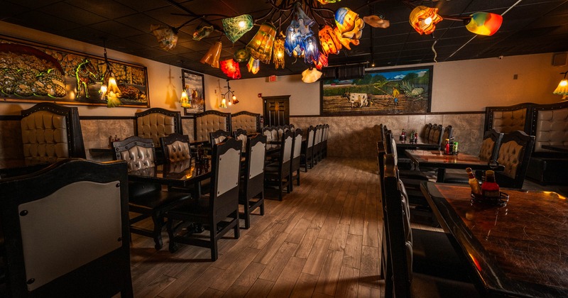 Interior with colorful glass chandeliers, wooden tables, and large paintings on the walls