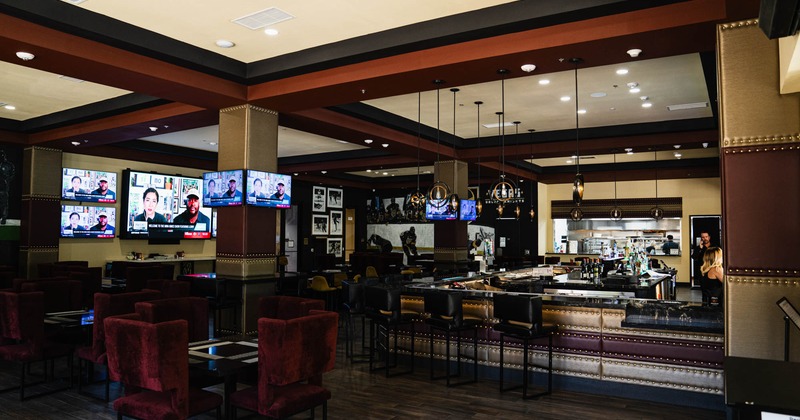 Seating area and bar with large TV screens on the walls