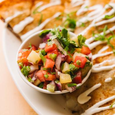 Quesadilla served with fresh pico de gallo salsa and drizzle, close up.
