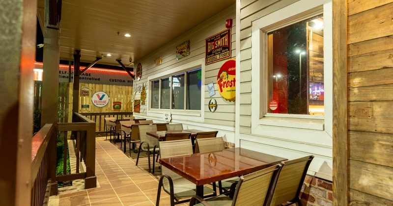 Outdoor seating area with tables and vintage signs on the wall