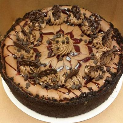 Decadent chocolate cheesecake garnished with chocolate swirls, chips, and drizzles.