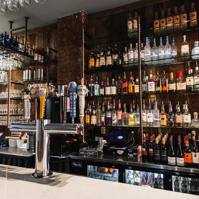 Numerous bottles on shelves behind the bar.