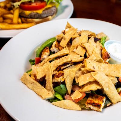 Salad with lettuce, Cajun spiced chicken, tomatoes, beans, corn, avocado, and tortilla strips.
