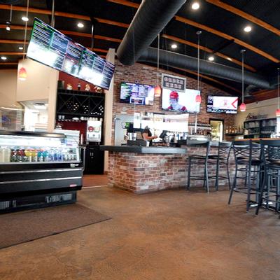 Interior, bar with tables and chair in front of it and a fridge with drinks on the left