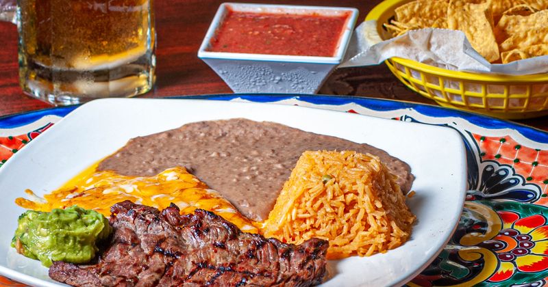 Tender steak with two cheese enchiladas served with guacamole and rice