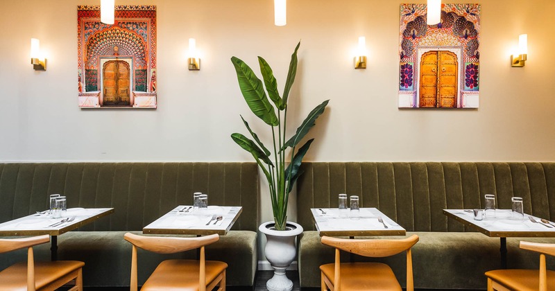 Interior, tables set for guests with long banquette seating and chairs
