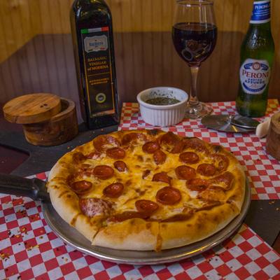 Pepperoni pizza accompanied by wine, beer, balsamic vinegar, and spices.