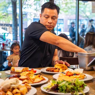 A person serving food at a table filled with various dishes.