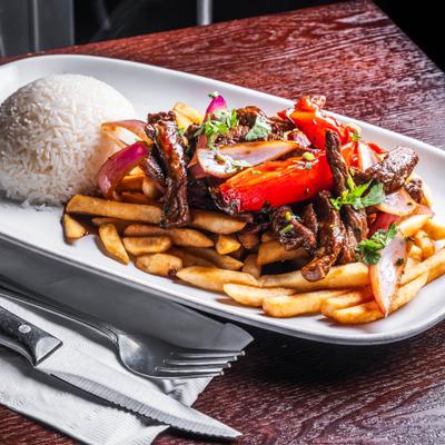 Marinated steak strips with fries, grilled onions, peppers, and rice.